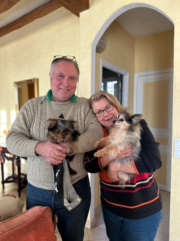A man and woman holding two small dogs indoors.